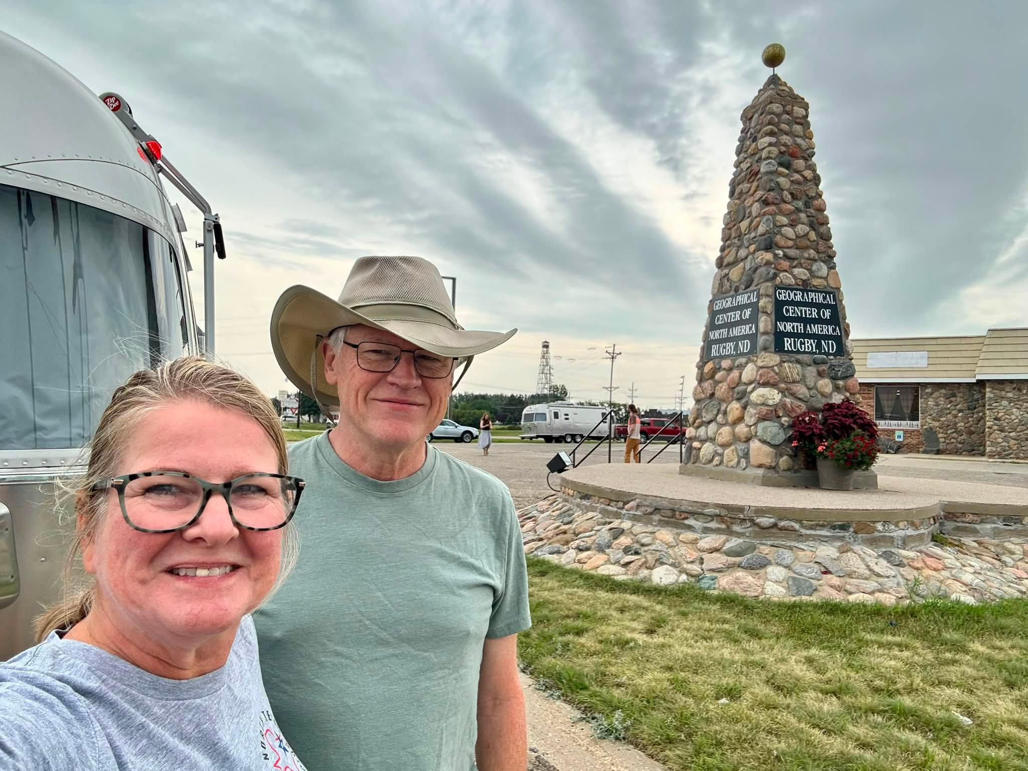 Tom and Sandra beside Belle at the stone cairn in Rugby, North Dakota, its plaques reading “Geographical Center of North America”