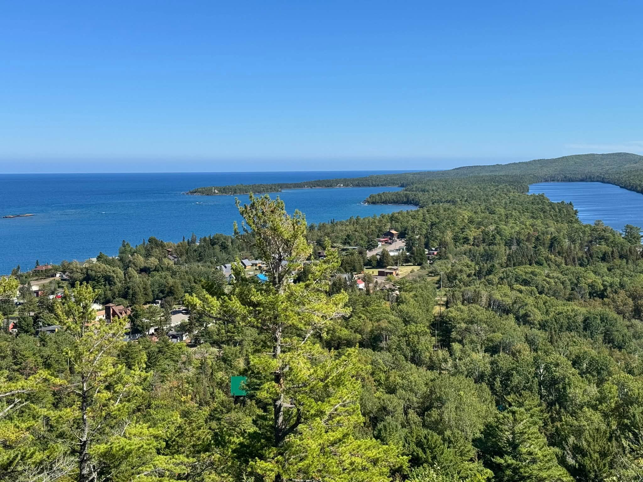 The view from Brockway Mountain down over the forested point and rooftops of Copper Harbor, the deep blue of Lake Superior wrapping around the headland on both sides